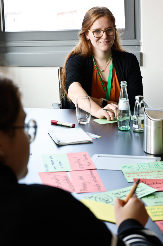 Lea lächelt am Tisch mit Metaplankarten